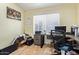 A cluttered office space with a large window, desk, and tiled flooring at 1619 E Aspen Ave, Buckeye, AZ 85326
