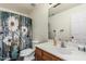 Full bathroom features a white vanity with a wood cabinet and a shower with a colorful curtain at 17611 W Watson Ln, Surprise, AZ 85388