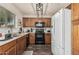 Well-equipped kitchen features wood cabinets, black appliances, modern light fixture, and a white refrigerator at 17611 W Watson Ln, Surprise, AZ 85388