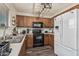 Updated kitchen with wooden cabinetry, black appliances, and stylish light fixture creates a modern cooking space at 17611 W Watson Ln, Surprise, AZ 85388