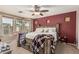 Cozy main bedroom features a red accent wall, ceiling fan, and natural light from windows overlooking the yard at 17611 W Watson Ln, Surprise, AZ 85388