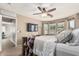 Serene main bedroom with soft colors, ceiling fan, TV, and abundant natural light from the windows at 17611 W Watson Ln, Surprise, AZ 85388