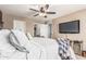 Relaxing main bedroom with soft colors, ceiling fan, TV, and doorways to closets and bathroom at 17611 W Watson Ln, Surprise, AZ 85388