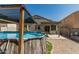 A backyard featuring an above-ground pool with ladder, patio, desert landscaping, and a partially covered patio area at 17611 W Watson Ln, Surprise, AZ 85388