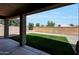 A covered backyard with a block fence, pavers, gravel, and artificial turf at 18371 W Capistrano Ave, Goodyear, AZ 85338