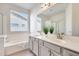 Bathroom featuring a modern vanity with double sinks, bright windows, and a large mirror at 18371 W Capistrano Ave, Goodyear, AZ 85338