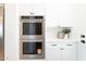 Close-up of stainless steel double ovens built into white cabinets with black hardware at 2095 N 77Th Pl, Mesa, AZ 85207