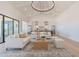 Bright, open-concept living room with white sofas, wood coffee table, and modern chandelier, seamlessly flowing into the kitchen at 2095 N 77Th Pl, Mesa, AZ 85207