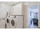 Bright laundry room with a front-load washer and dryer with overhead storage cabinets at 21061 N 33Rd Dr, Phoenix, AZ 85027