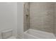 Modern bathroom with stylish gray subway tile shower, built-in niche, and a white bathtub at 21276 W Mariposa St, Buckeye, AZ 85396