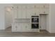 Bright kitchen features white cabinets, stainless double oven, and light stone countertops at 21276 W Mariposa St, Buckeye, AZ 85396