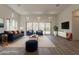 Staged living room with neutral walls, wood floors, large windows, modern furniture, and a sliding glass door at 21276 W Mariposa St, Buckeye, AZ 85396