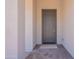 A tidy, sheltered front porch features a gray front door and a decorative doormat for a warm welcome at 21427 W Meadowbrook Ave, Buckeye, AZ 85396