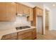 Kitchen with wood cabinets, white subway tile backsplash, quartz countertops, and stainless steel gas cooktop at 21427 W Meadowbrook Ave, Buckeye, AZ 85396