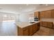 Spacious kitchen with wood cabinets, a large island with quartz countertops, and open access to the living room at 21427 W Meadowbrook Ave, Buckeye, AZ 85396