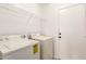 Bright laundry room with white washer, dryer, overhead rack and access door at 22547 W Pima St, Buckeye, AZ 85326