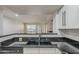 Close-up of a kitchen sink with black countertops, white cabinets, and stainless steel appliances at 2333 E Southern Ave # 1023, Tempe, AZ 85282
