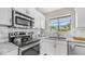 Updated kitchen with white cabinets, stainless steel appliances, granite countertops, and bright window at 3844 E Shomi St, Phoenix, AZ 85044