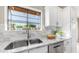 Well-lit kitchen featuring a stainless steel sink, granite countertops, white cabinets, and backyard view at 3844 E Shomi St, Phoenix, AZ 85044