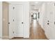 Well-lit hallway with wood-look flooring and white doors, leading to various rooms in the home at 42400 W Peters Dr, Maricopa, AZ 85138