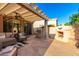 Inviting covered patio with ample seating, stone floors, built-in grill and fireplace at 4637 E Narrowleaf Dr, Gilbert, AZ 85298