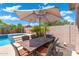 Outdoor dining under a large umbrella by the pool, surrounded by lush landscaping and serene ambiance at 5123 W Redbird Rd, Phoenix, AZ 85083