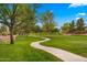 Curving sidewalk through a lush green park with mature trees and manicured landscaping at 549 E Benrich Dr, Gilbert, AZ 85295
