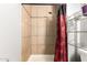 Tiled shower stall with tan tile and red and black shower curtain at 6335 W Osborn Rd, Phoenix, AZ 85033