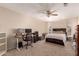 Bedroom featuring ceiling fan, dark wood bed frame, and workstation at 7724 W Oraibi Dr, Glendale, AZ 85308