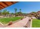 Lush backyard showcasing a well-manicured lawn, paved walkway, mature trees and desert landscaping at 8043 E Laurel St, Mesa, AZ 85207