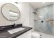 Modern bathroom with a sleek black countertop, round mirror, and stunning stone shower at 8252 E Heatherbrae Ave, Scottsdale, AZ 85251