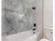 Stylish bathtub with beautiful stone tiling, black fixtures, and shower at 8252 E Heatherbrae Ave, Scottsdale, AZ 85251