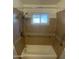 Walk-in shower and tub combination with tiled walls and window at 10910 N 72Nd Dr, Peoria, AZ 85345