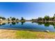 Serene lake view with reflections of waterfront homes and lush trees under a clear blue sky at 11026 N 28Th Dr # 81, Phoenix, AZ 85029