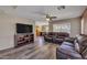 Living room with wood floors, large windows, ceiling fan, and a comfortable leather sofa at 12720 W Cantenia Rd, Avondale, AZ 85392