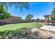 Large backyard with green grass, shade trees, an outdoor pergola with seating, and block fence at 1359 E 12Th St, Casa Grande, AZ 85122