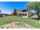 Back exterior view of two-story home with large lawn, backyard pergola seating area, and mature shade trees at 1359 E 12Th St, Casa Grande, AZ 85122
