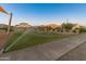 View of a community area with irrigation system watering the turf, and houses in the background at 14274 W Sand Hills Rd, Surprise, AZ 85387