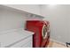 Laundry room showcasing red front-loading machines, white cabinets, and tiled floors at 14274 W Sand Hills Rd, Surprise, AZ 85387