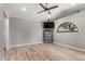 Bright bedroom featuring wood-look floors, a ceiling fan, a wall-mounted TV and an arched window at 1534 E Mineral Rd, Gilbert, AZ 85234