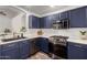 Kitchen with stainless steel appliances, stylish blue cabinets, and wood-look flooring at 16118 W Morning Glory St, Goodyear, AZ 85338