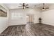 Bright open living room with a sliding glass door, ceiling fan, and wood-look floors at 16118 W Morning Glory St, Goodyear, AZ 85338