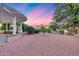 Landscaped backyard with gravel, mature trees, and covered patio at 17911 N Adobe Mesa Ct, Surprise, AZ 85374
