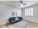 Cozy bedroom featuring a modern blue sofa, a ceiling fan, and shuttered windows at 17911 N Adobe Mesa Ct, Surprise, AZ 85374