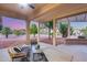 Covered patio with seating area offering a serene view of the landscaped backyard at 17911 N Adobe Mesa Ct, Surprise, AZ 85374