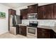 Modern kitchen featuring stainless steel appliances, granite countertops, and dark wood cabinetry at 22403 W Harrison St, Buckeye, AZ 85326