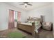 Comfortable main bedroom with plush carpet, a decorative wood bed frame, and soft pink curtains at 22403 W Harrison St, Buckeye, AZ 85326