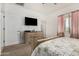 Bright main bedroom featuring plush carpet, tv, decorative headboard, and soft pink curtains at 22403 W Harrison St, Buckeye, AZ 85326