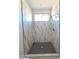 Stylish walk-in shower with white marble walls, black honeycomb tile and a window at 28151 N Faded Creek Dr, Florence, AZ 85132