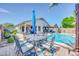 Inviting backyard featuring a sparkling pool, dining set, and covered patio, perfect for outdoor entertaining at 46068 W Guilder Ave, Maricopa, AZ 85139